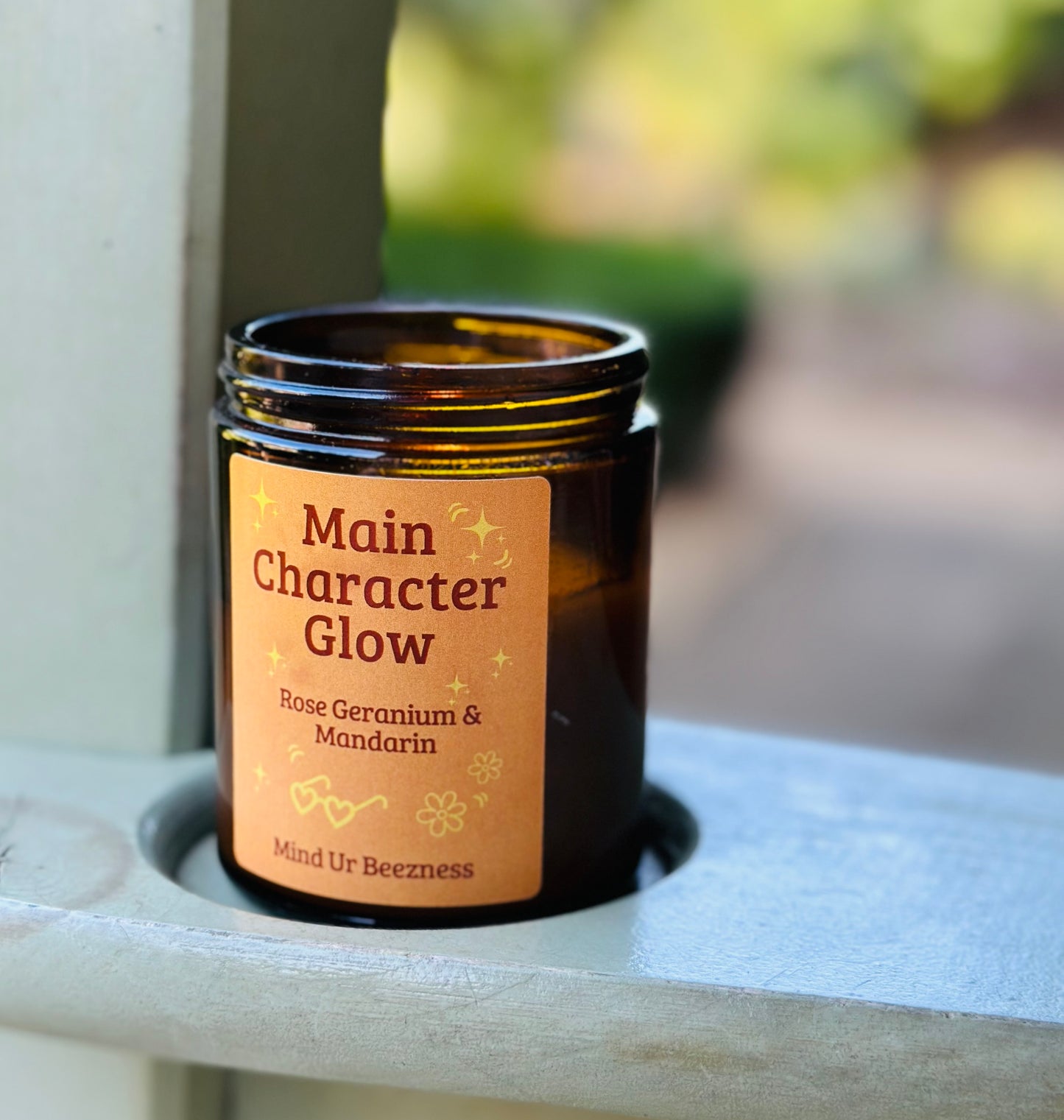 Amber jar candle with “Main Character Glow” label by Mind Ur Beezness, rose geranium and mandarin scent, soft girl aesthetic gift
