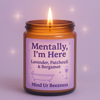 Close-up of the “Mentally, I’m Here” candle by Mind Ur Beezness, featuring a lavender, patchouli & bergamot blend, set against a dreamy purple soft girl background with sparkles.
